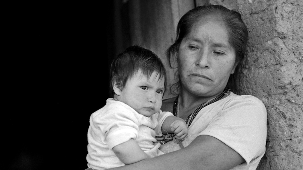 A woman carries her son, who has markings on his face. She is concerned that he will develop the same symptoms as other children in the village [Prometeo Lucero]