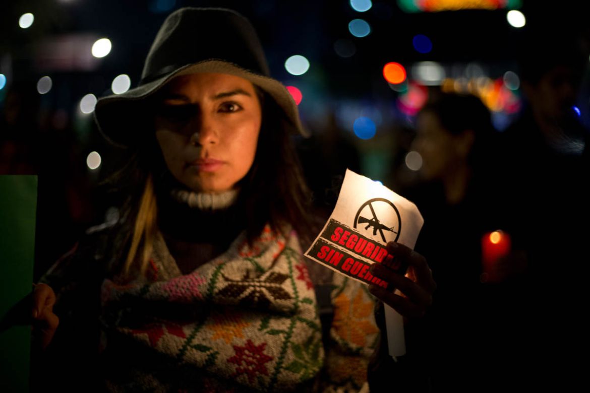 A woman carries a sign that says in Spanish "Security without war" during a candlelight protest against a newly proposed security law in Mexico City, late Wednesday, Dec. 13, 2017. Mexico''s ruling par