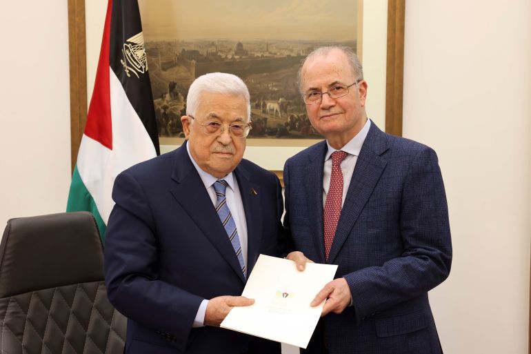 Palestinian President Mahmoud Abbas (L) poses for a photo with former Deputy Prime Minister and Chairman of the Palestinian Investment Fund Mohammed Mustafa (R) after appointed him as the new Prime Minister in Ramallah