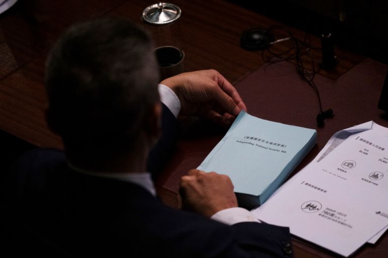 A lawmaker holds a copy of the proposed Safeguarding National Security Bill during the second reading of the Basic Law Article 23 legislation at the Legislative Council in Hong Kong, Tuesday, March 19, 2024