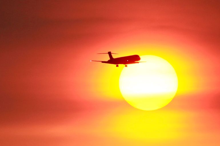 A plane flies past a setting sun near the Songshan airport in Taipei July 20, 2009. REUTERS/Nicky Loh (TAIWAN TRANSPORT ENVIRONMENT IMAGES OF THE DAY)