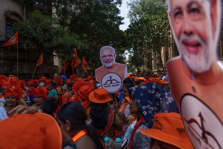 Supporters of National Democratic Alliance walk in a road show holding cutout photos of Indian Prime Minister Narendra Modi as their candidates arrive to file nomination papers ahead of national elections in Mumbai, India, Monday, April 29, 2024. (AP Photo/Rafiq Maqbool)